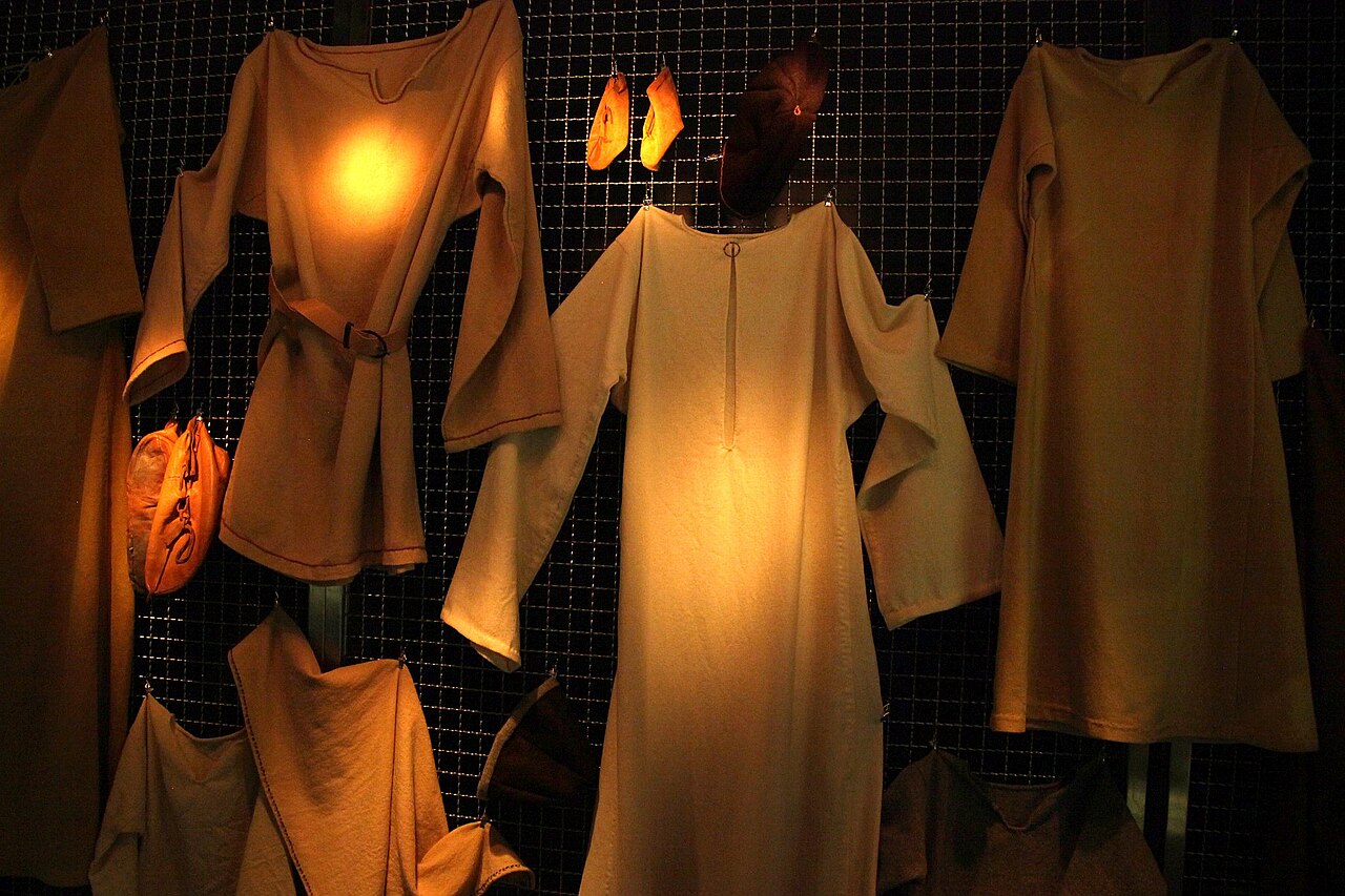 Reconstructed Viking Age clothing on display, showing layered wool tunics and a woman's apron dress